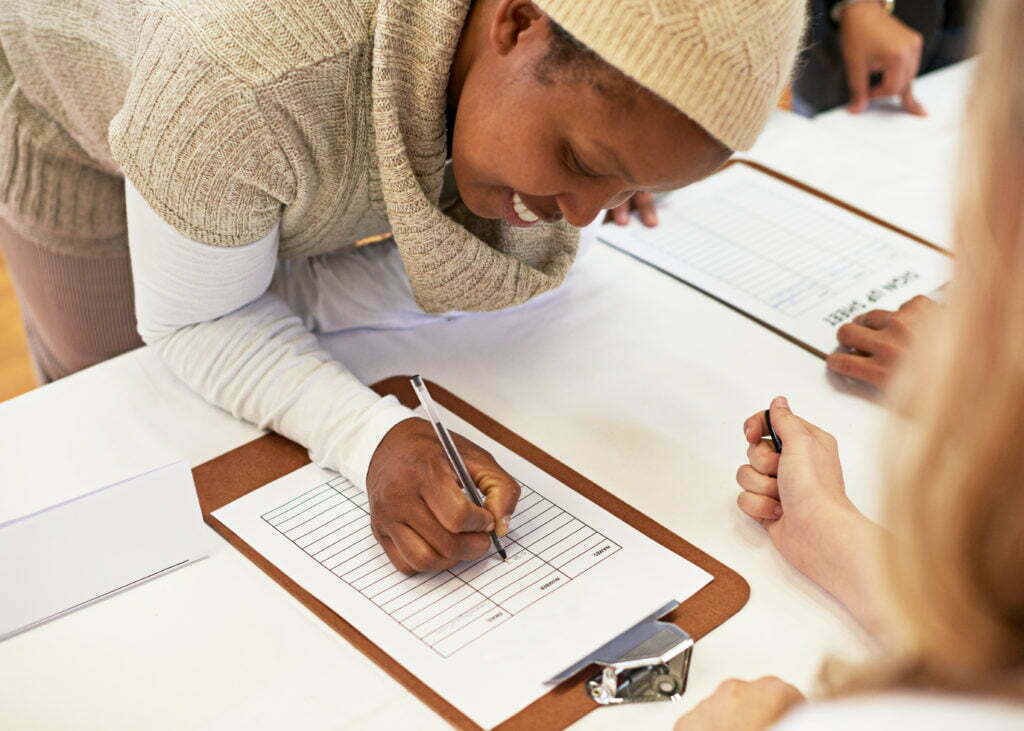 An African-American woman signing a disaster volunteer registration form.