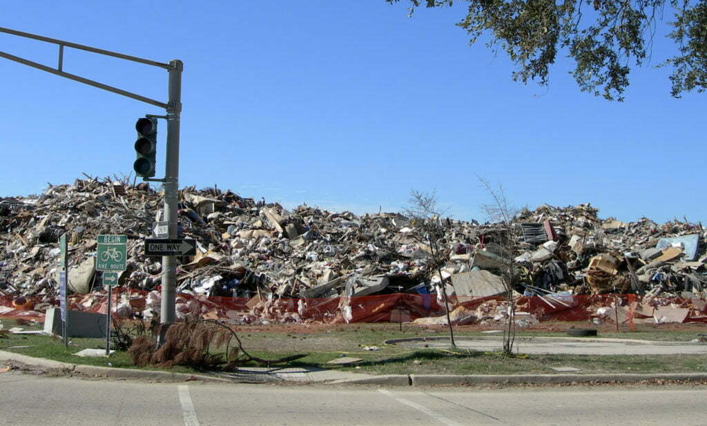 A massive pile of debris left from homes destroyed in Hurricane Katrina sits several feet high in a pile on the side of a deserted street.