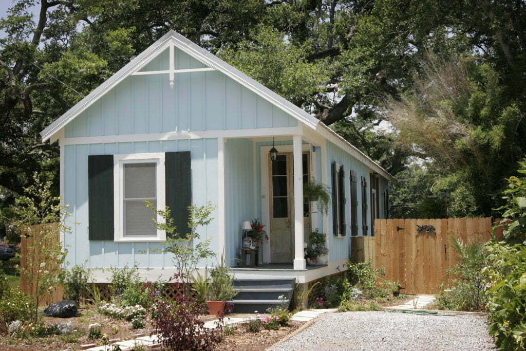 The front view of a blue, one-story cottage and its garden built in Mississippi after Hurricane Katrina