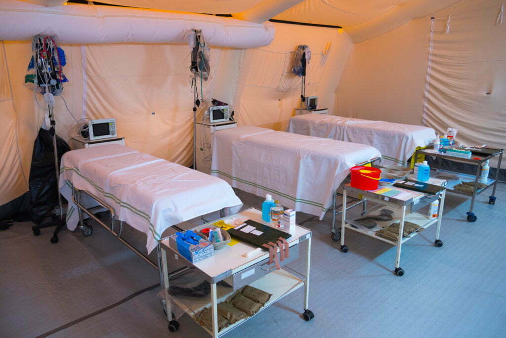 Hospital beds and medical supplies lined up inside a medical tent