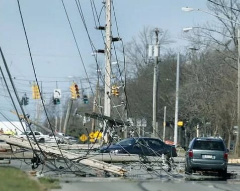 Abandoned cars sit amidst downed power lines and roads on a suburban street.