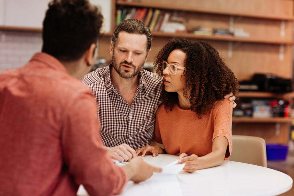 A biracial couple reviewing paperwork with their disaster assistance case manager.