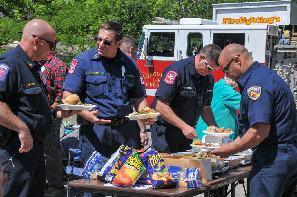 Emergency medical workers stand around a table scooping food onto their plates during a break from service.