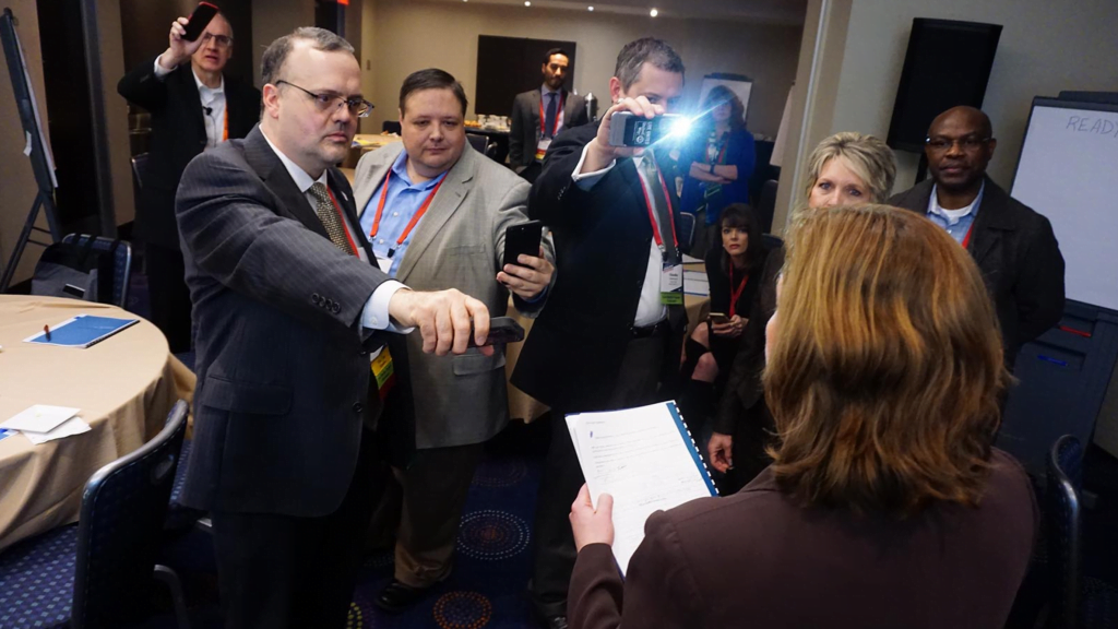 Media representatives hold out microphones and cameras during an interview with a county official.